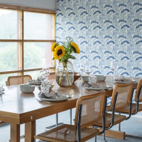 Tapetissa on vaaleansinisiä marjoja, tummansinisiä kukkia ja vaaleanvihreitä lehtiä valkoisella pohjalla.